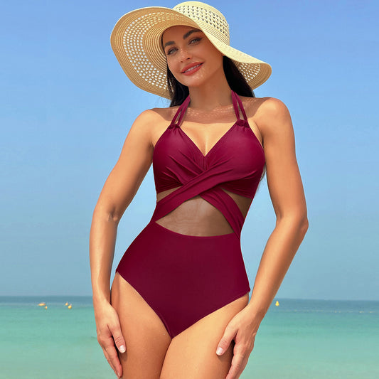 Woman in a green halter-neck one-piece swimsuit with cross-strap design and mesh cutouts, on a beach. - Image 2