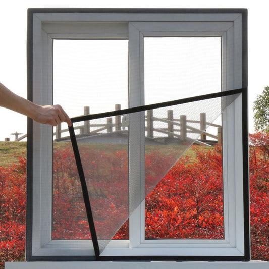 White mosquito screen applied to a window, with a hand gently pulling a corner to show its fine mesh texture.