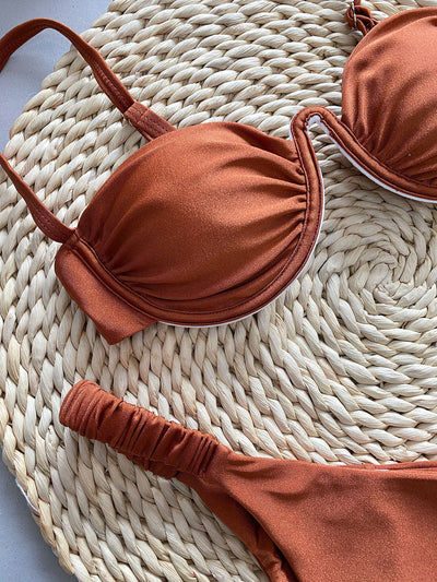 Rust underwire bikini set with ruched top and high-cut bottom, displayed on a woven mat. - Image 22