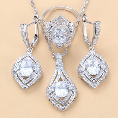 Silver-toned three-piece jewelry set with clear oval and round gems, including a necklace, dangle earrings, and a ring. - Image 9