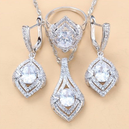 Silver-toned three-piece jewelry set with clear oval and round gems, including a necklace, dangle earrings, and a ring. - Image 9