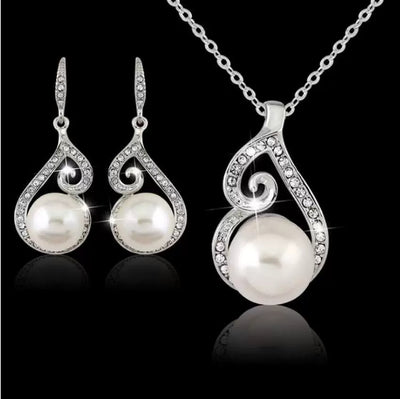 Silver-tone rhinestone and faux pearl drop necklace and matching earrings jewelry set on a black background. - Image 6