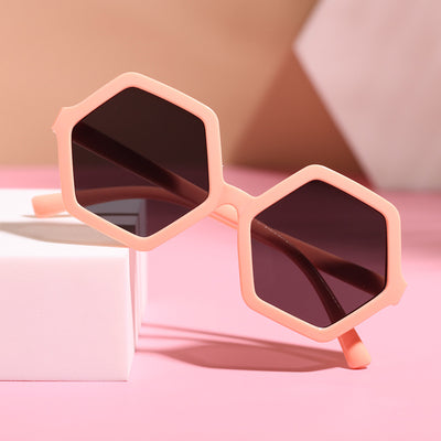 Red hexagonal children's sunglasses with dark lenses on a pink surface with a white block. - Image 8