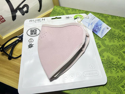 Dark gray cotton head-mounted mask with adjustable ear loops, shown in packaging on a patterned green surface. - Image 11