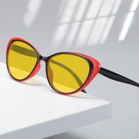 Retro cat-eye sunglasses with bright black frames and yellow night vision lenses on a white background.