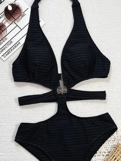 Woman in a black ribbed one-piece swimsuit with a halter neck, side cut-outs, and a starfish ring detail, lying on a white towel. - Image 11