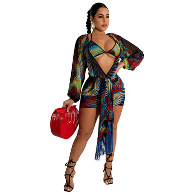 Model wearing a blue, red, and yellow abstract print three-piece mesh swimsuit set with a bikini top, mini skirt, and long-sleeve cover-up. - Image 6