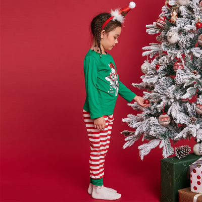 Child wearing green Christmas pajamas with a giraffe graphic and red striped pants, next to a flocked tree. - Image 5