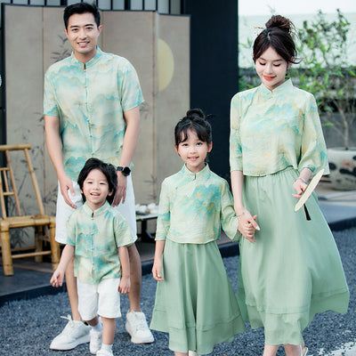 Mother and daughter in matching light green Chinese style cheongsam suits with patterned tops and solid skirts.