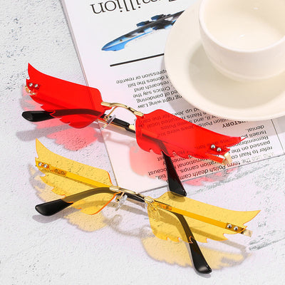 Purple wing-shaped rimless sunglasses with gold-colored metal arms and black ear tips on a white background.