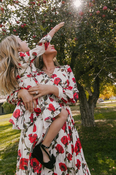 Mother and daughter in matching white dresses with red floral print, V-neck, long sleeves, and tie-waist. - Image 6