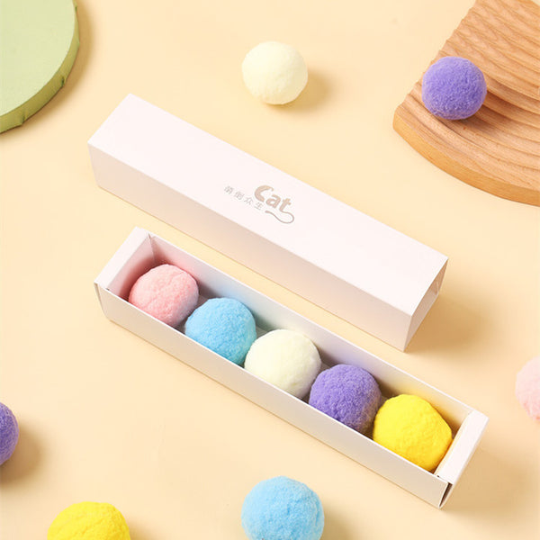 Five colorful plush balls in a white gift box, including pink, yellow, blue, purple, and bright yellow.