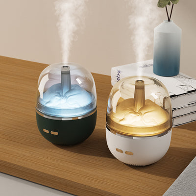 White essential oil diffuser and humidifier with a clear dome top, glowing red inside, and blue LED base light.