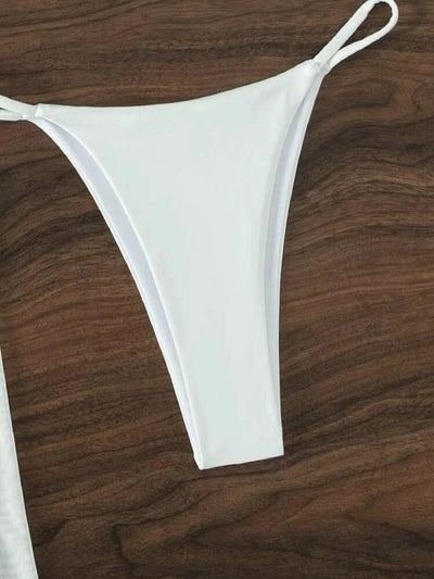 White three-piece halter neck bikini and sheer cover-up set with a heart-shaped embellishment, laid flat on wood. - Image 13