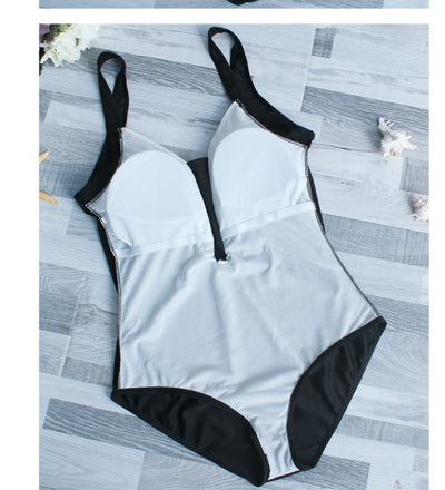 Woman in black one-piece swimsuit with white trim, wide-brimmed hat, and striped tote bag on a sunny beach. - Image 11