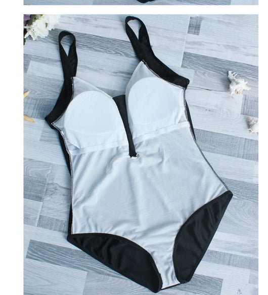 Woman in black one-piece swimsuit with white trim, wide-brimmed hat, and striped tote bag on a sunny beach. - Image 11