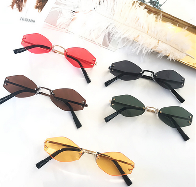 Retro oval vintage sunglasses with orange hexagonal lenses and gold-tone metal temples, held by a hand.