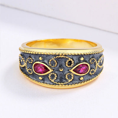Gold-toned wide band ring with dark gray enamel, intricate scrollwork, and two fuchsia teardrop gemstones. - Image 3