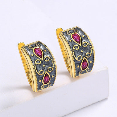 Gold-toned wide band ring with dark gray enamel, intricate scrollwork, and two fuchsia teardrop gemstones. - Image 5