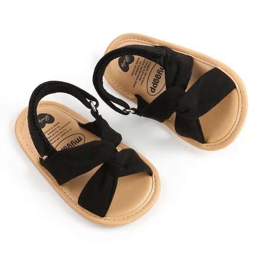 Black baby sandals with knotted cross straps and a matching black floral headband on a white background. - Image 15