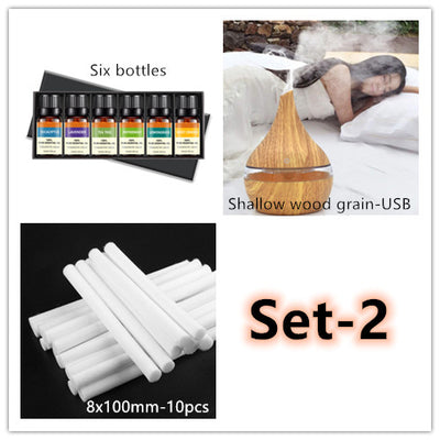 Dark wood grain LED essential oil diffuser with a blue light band and touch switch, shown with a hand operating it. Includes a bundle of 10 white filter sticks. - Image 9
