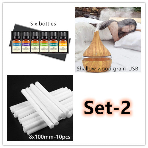 Dark wood grain LED essential oil diffuser with a blue light band and touch switch, shown with a hand operating it. Includes a bundle of 10 white filter sticks. - Image 9