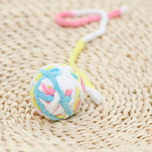 Colorful plush yarn ball cat toy in pink, blue, and white, with a long trailing strand, on a light background. - Image 43