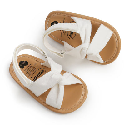 Black baby sandals with knotted cross straps and a matching black floral headband on a white background. - Image 19