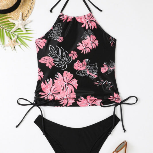 Black halter-neck tankini swimsuit with pink and white floral print, paired with solid black high-cut bikini bottoms.