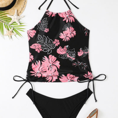 Black halter-neck tankini swimsuit with pink and white floral print, paired with solid black high-cut bikini bottoms.