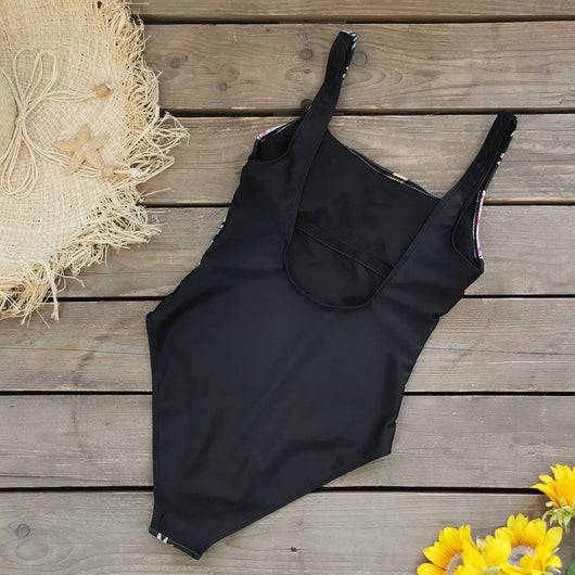 Black one-piece swimsuit for women featuring a vibrant multi-color print with dragons, suns, moons, and stars. - Image 3