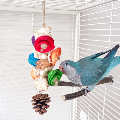 Blue parrot playing with a colorful natural material bird toy featuring corn cobs, wood, and pinecones, hanging in a white birdcage. - Image 9