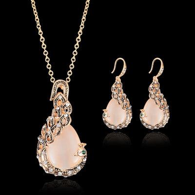 Rose gold tone bridal jewelry set with a necklace and stud earrings, each featuring a large blue teardrop gem and clear accents. - Image 2
