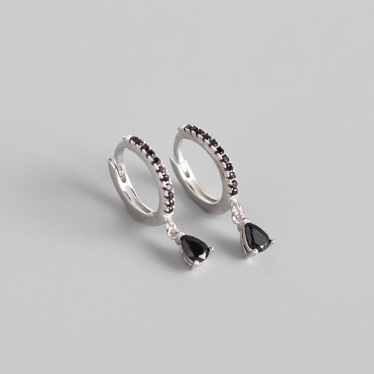 Silver-colored hoop earrings with black pave stones and dangling black teardrop-shaped stones.