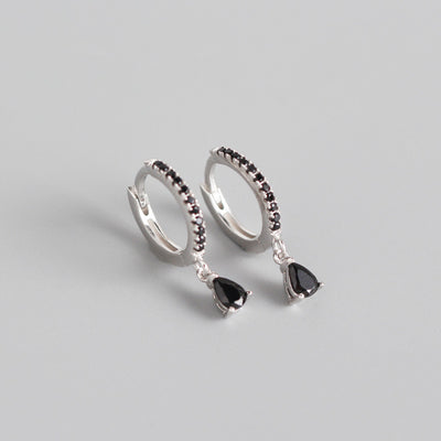 Silver-colored hoop earrings with black pave stones and dangling black teardrop-shaped stones.