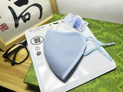 Dark gray cotton head-mounted mask with adjustable ear loops, shown in packaging on a patterned green surface. - Image 20