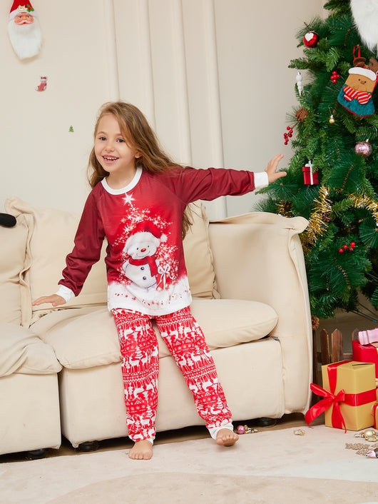 Family of four wearing matching red Christmas pajamas with snowman tops and reindeer fair isle pants, sitting by a Christmas tree. - Image 8