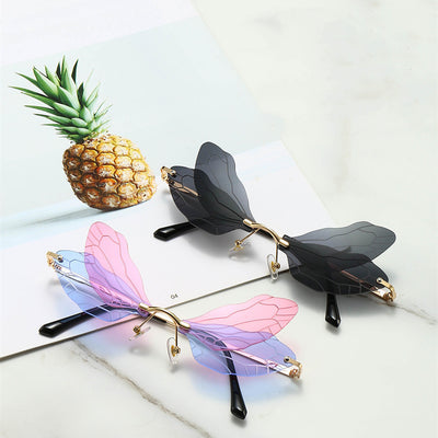 Frameless sunglasses with pink and orange-yellow dragonfly wing-shaped lenses and gold-colored metal temples.