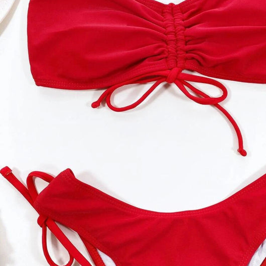 Red two-piece bikini with a strapless ruched bandeau top and matching side-tie bottoms, displayed on a white surface. - Image 13