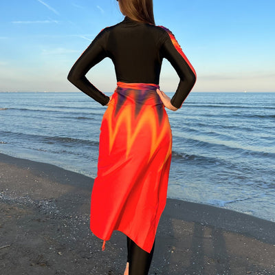 Woman in a black long-sleeve rash guard, black swim leggings, and a vibrant tie-dye sarong on a sunny beach. - Image 4