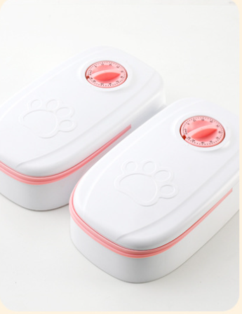 White automatic pet feeder with a pink timer dial and an embossed paw print on the lid. - Image 10