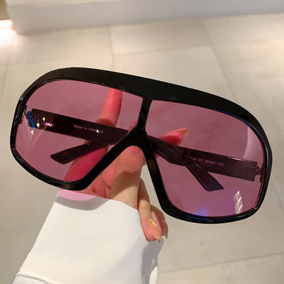 Oversized women's shield sunglasses with a tortoiseshell frame and brown-tinted lenses, held by a hand. - Image 4