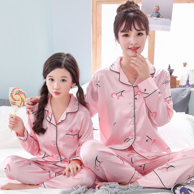 Mother and daughter in matching light blue satin pajamas with pink cherry print, sitting on a gray sofa. - Image 3