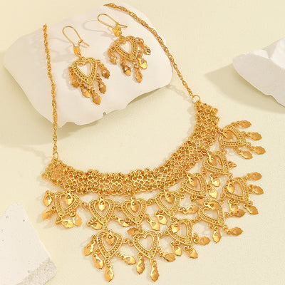 Gold heart-shaped hollow necklace and matching dangle earrings set on a woman wearing a black top. - Image 4