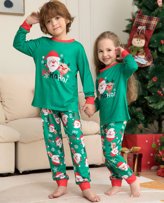 Family of four wearing matching green Christmas pajamas with Santa Claus and reindeer print, sitting on a sofa. - Image 2