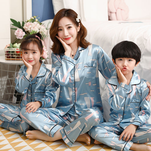 Mother and daughter in matching light blue satin pajamas with pink cherry print, sitting on a gray sofa. - Image 16