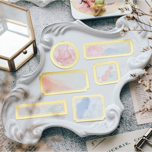 Assorted decorative paper labels with gold foil borders and soft watercolor designs in pink, blue, and green hues. - Image 4