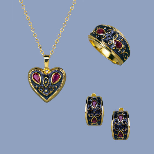 Gold-toned wide band ring with dark gray enamel, intricate scrollwork, and two fuchsia teardrop gemstones.