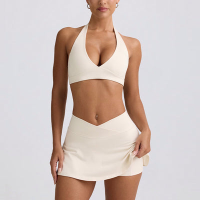 Light pink halter neck sports bra and high-waisted leggings workout set on a model.