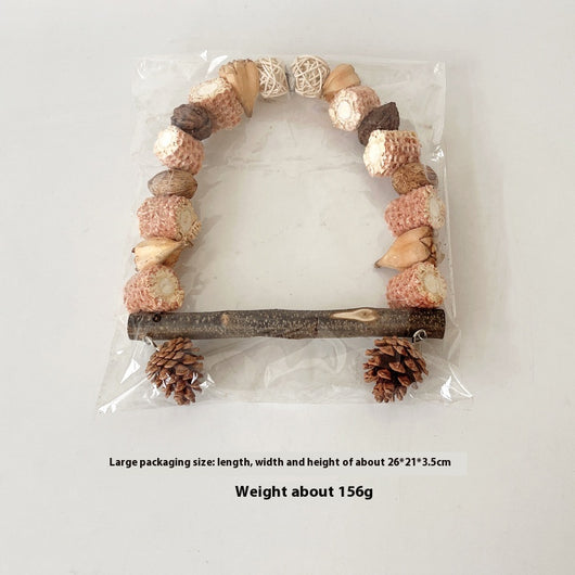 Natural wooden parrot swing with an arched top made of corn cobs, seed pods, and woven balls, featuring a log perch and two hanging pine cones. - Image 10